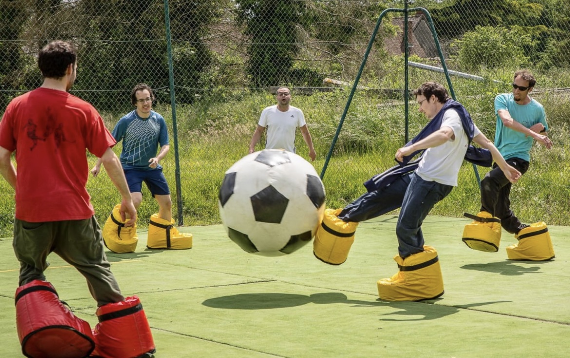 Joueurs en chaussures gonflables Crazy Big Foot frappant un ballon géant, location PACA